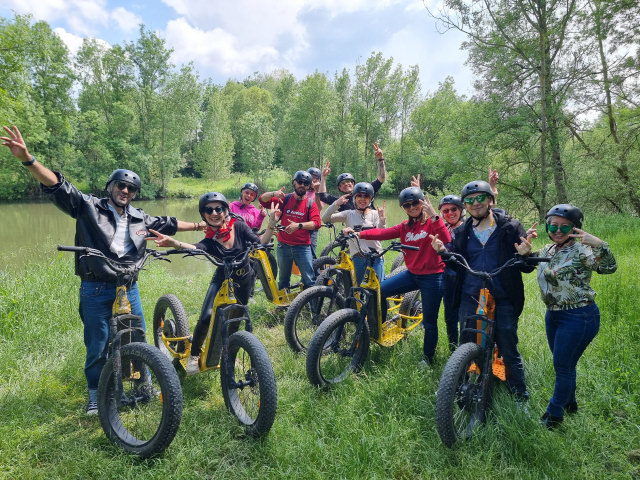 Groupe d'une dizaine de personne sur des trottinettes tout terrains électriques, dans une clairière